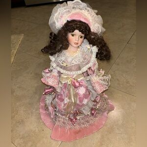 Pink and white porcelain doll with a pretty dress, hat, and bow